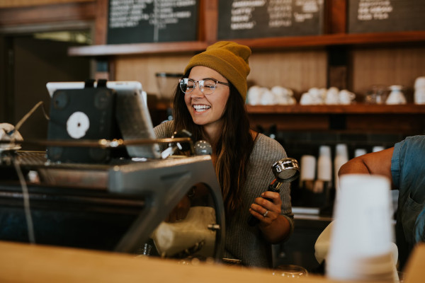Junge Frau arbeitet in Caf&eacute; an einer Kaffeemaschine