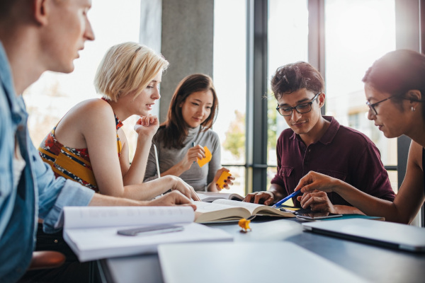 Gruppe die zusammen an einem Tisch mit B&uuml;chern und Skripten arbeitet