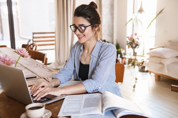 Junge Frau arbeitet in einem hellen Wohnzimmer am Laptop